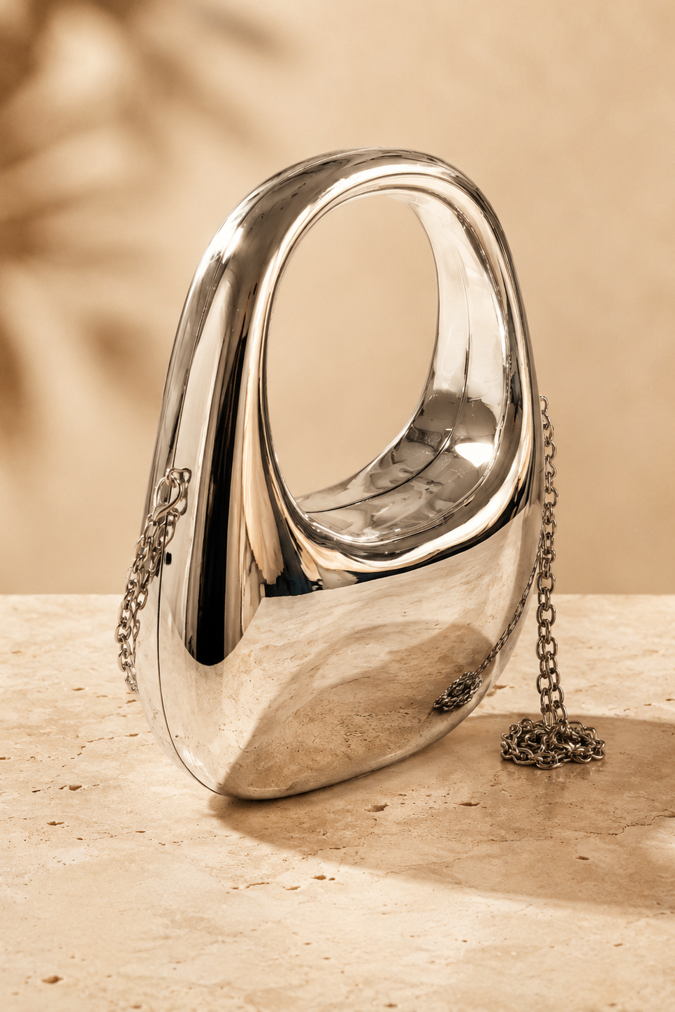 Bolso clutch plateado metalizado de diseño ovalado con cadena extraíble para bodas, fiestas y eventos elegantes.