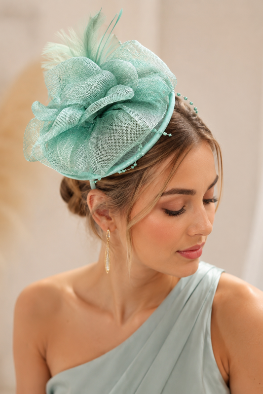 Tocado de fiesta verde agua de sinamay con plumas sobre diadema para invitada de boda elegante